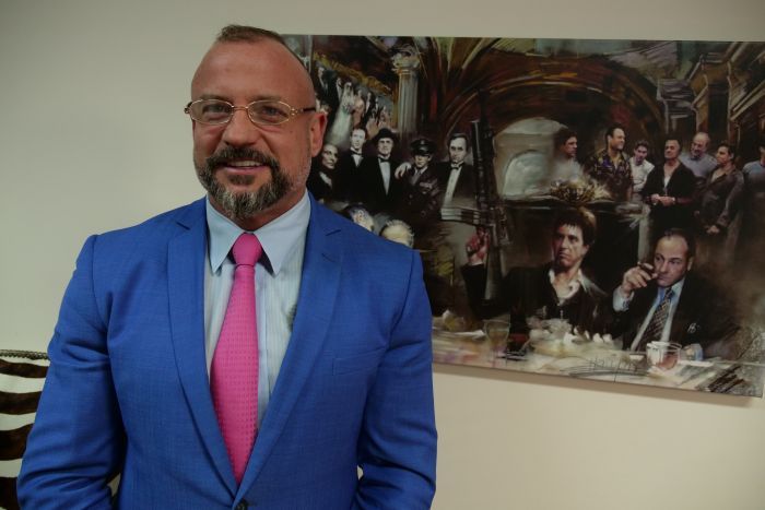 Lawyer, Campbell McCallum, standing in front of painting of gangsters